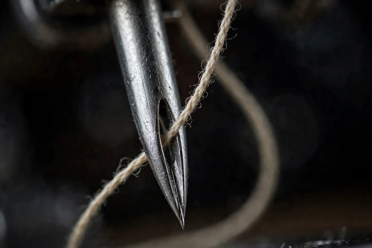 Extreme close-up of a sewing machine needle with thread through the eye